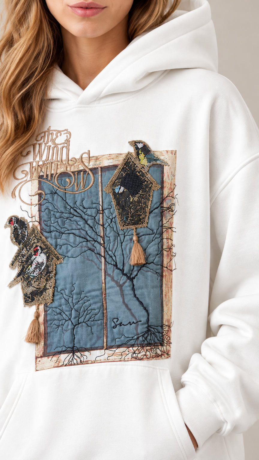 Close-up detail of artistic bird and window graphic on white hoodie chest