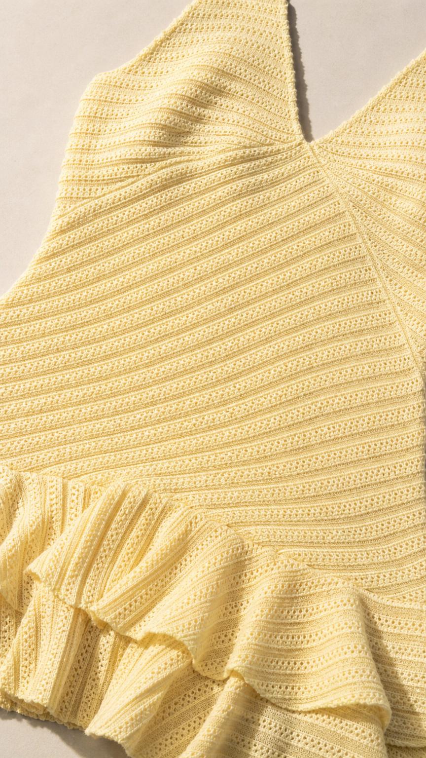 Close-up detail of yellow knit texture and ruffle hem
