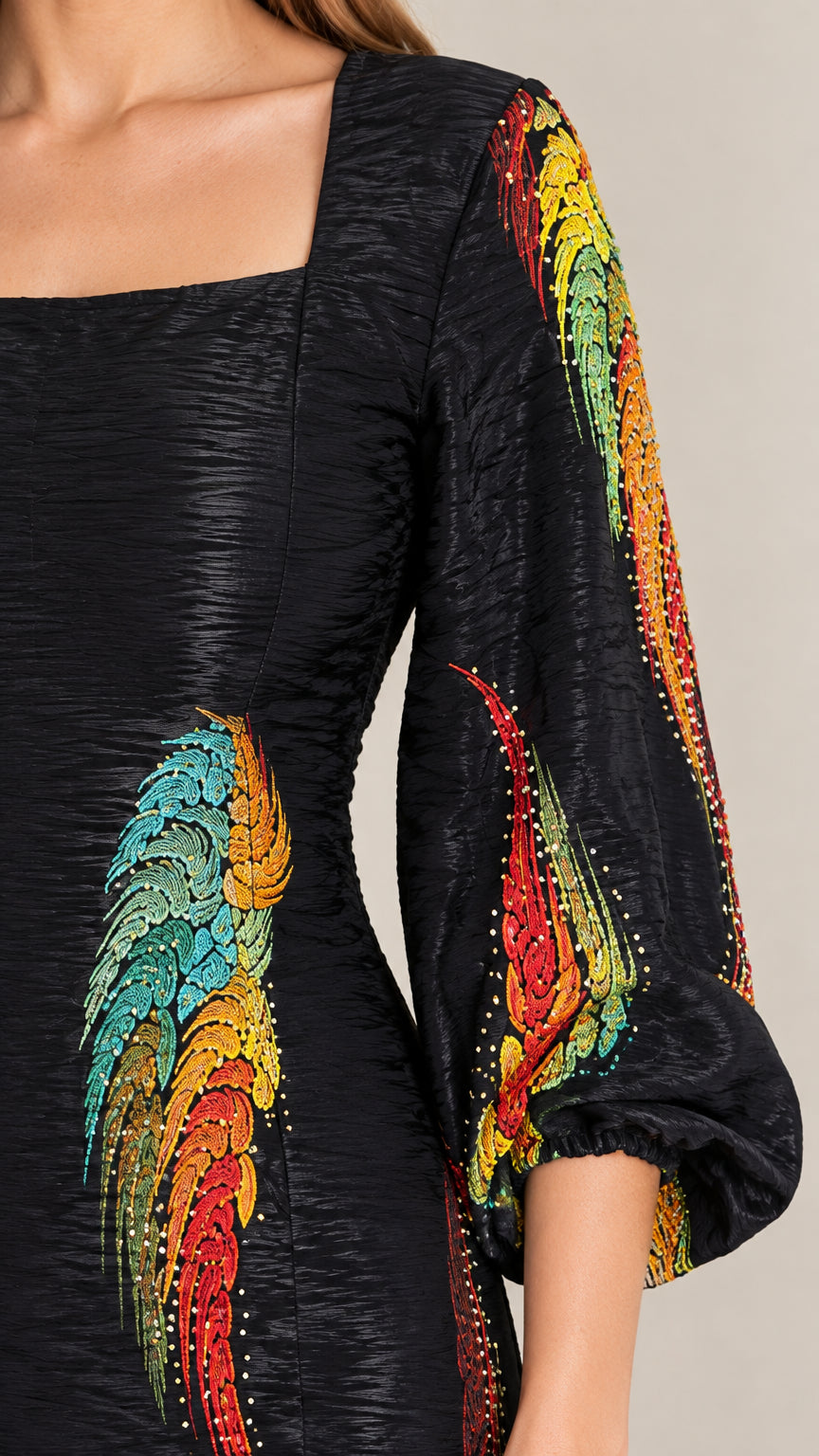 Close-up detail of textured fabric, square neckline, and colorful feather print embellishment