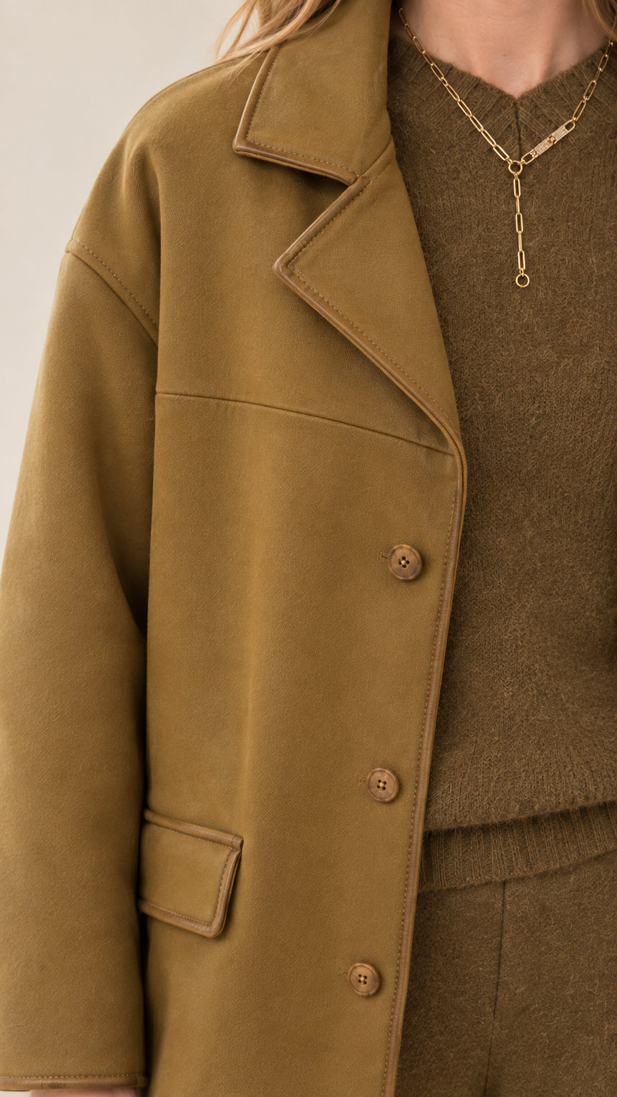 Close-up detail of lapel collar, buttons, and knit top in camel brown