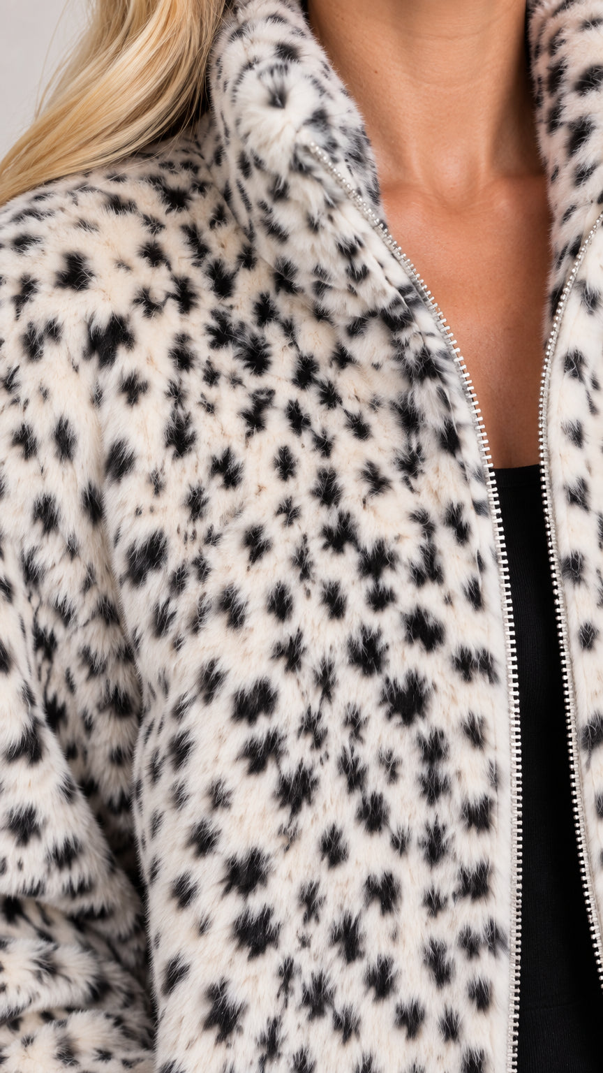 Close-up detail of white leopard print plush faux fur texture and silver zipper