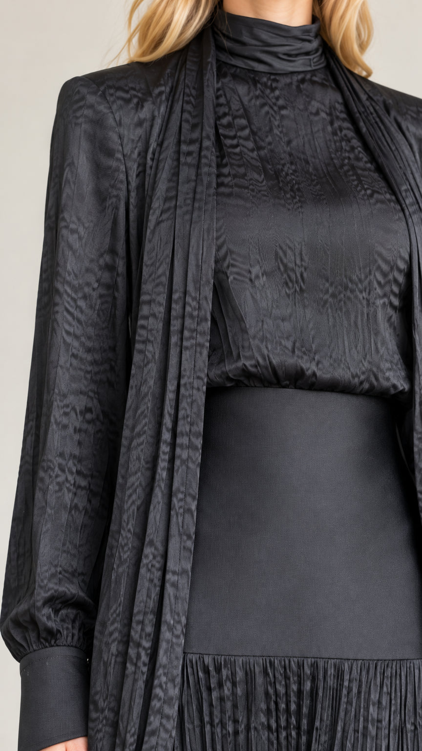 Close-up detail of black mock neck, textured fabric, wide waistband, and draped cardigan
