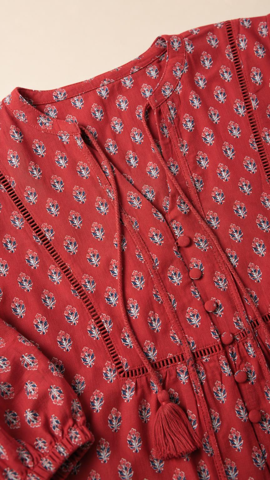 Close-up detail of V-neckline and button trim on red top