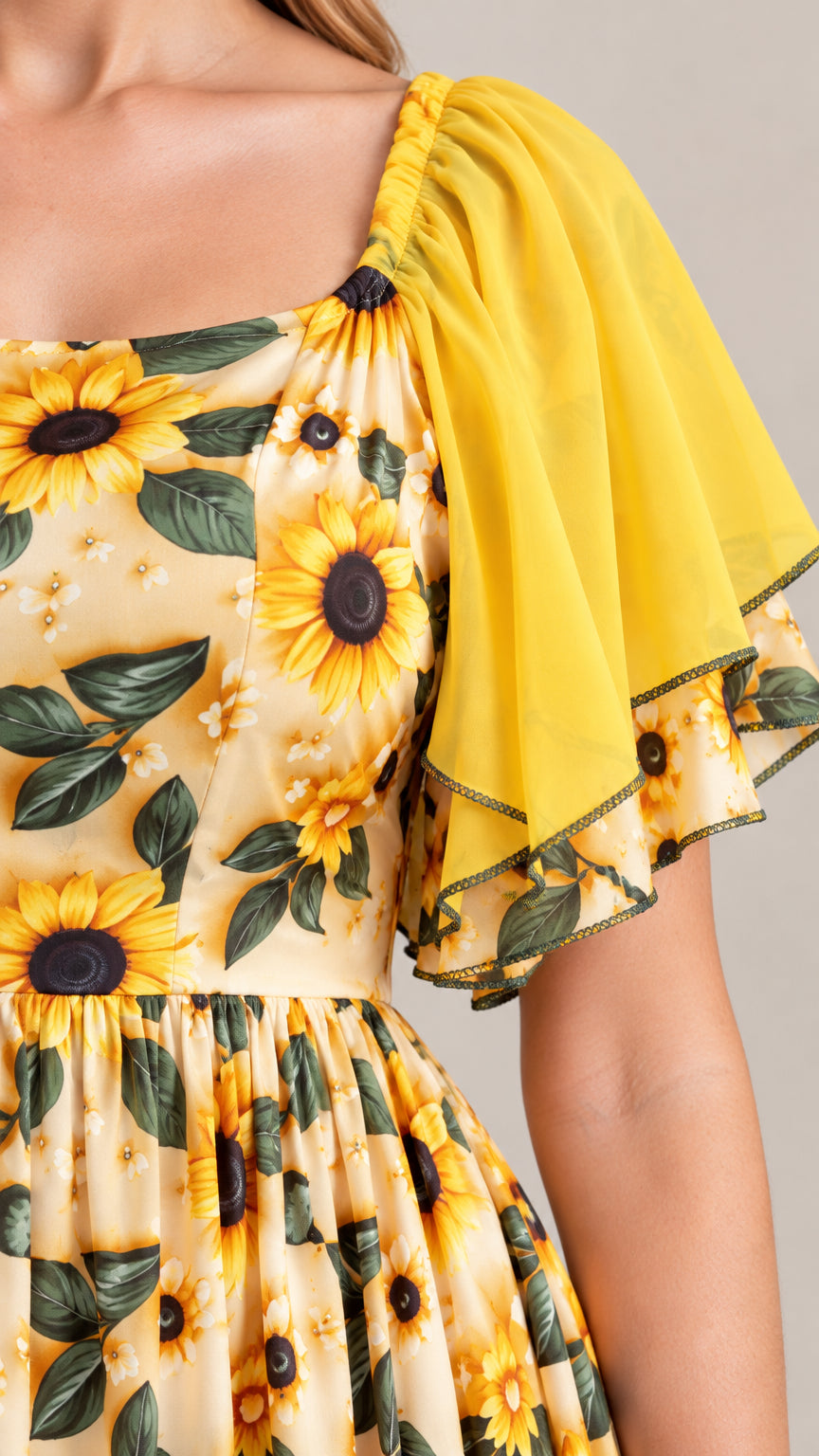 Close-up detail of square neckline and sheer yellow chiffon flutter sleeve