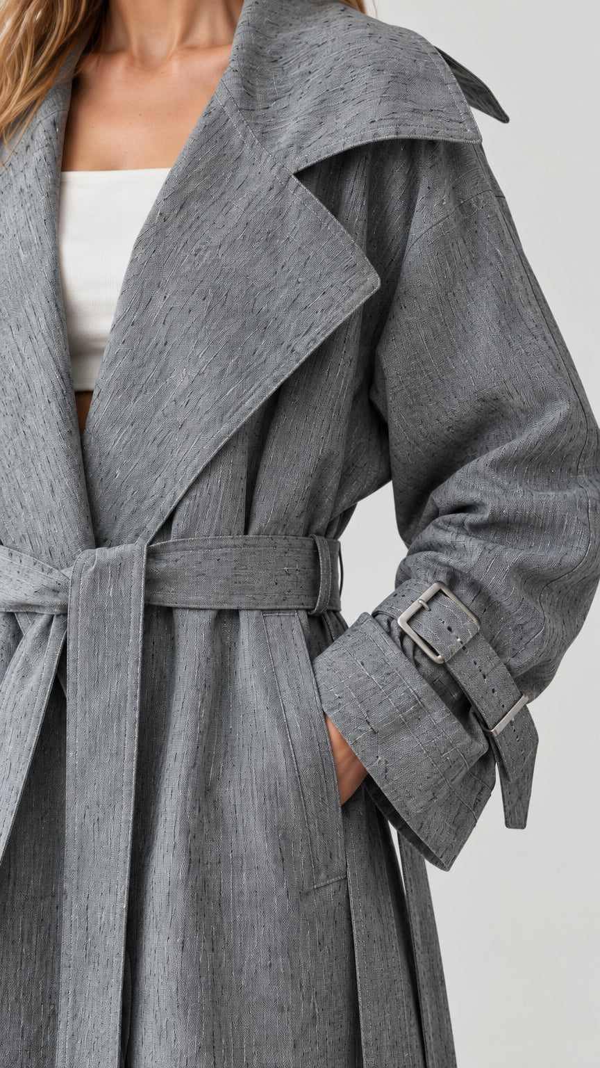Close-up of grey textured fabric, wide lapel collar, pocket, and belted cuff
