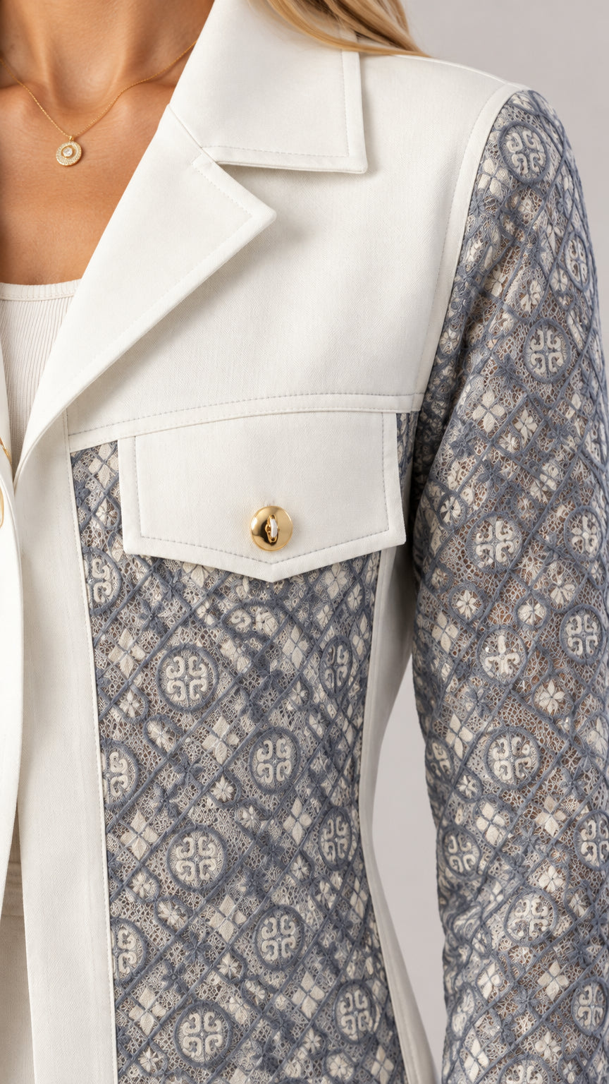 Close-up detail of notched lapel, flap pocket with gold button, and textured pattern
