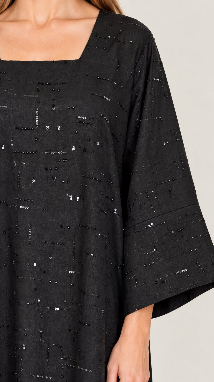 Close-up detail of square neckline and linear sequin pattern on black dress