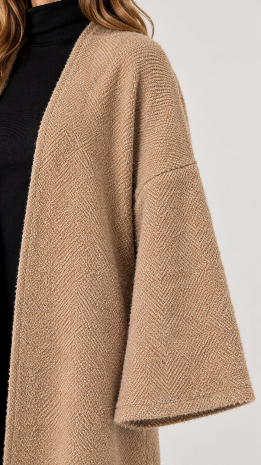 Close-up detail of camel textured knit fabric and wide bell sleeve