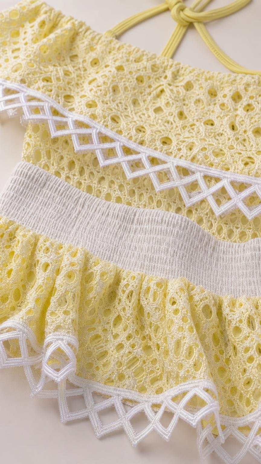Close-up detail of yellow eyelet lace and geometric trim