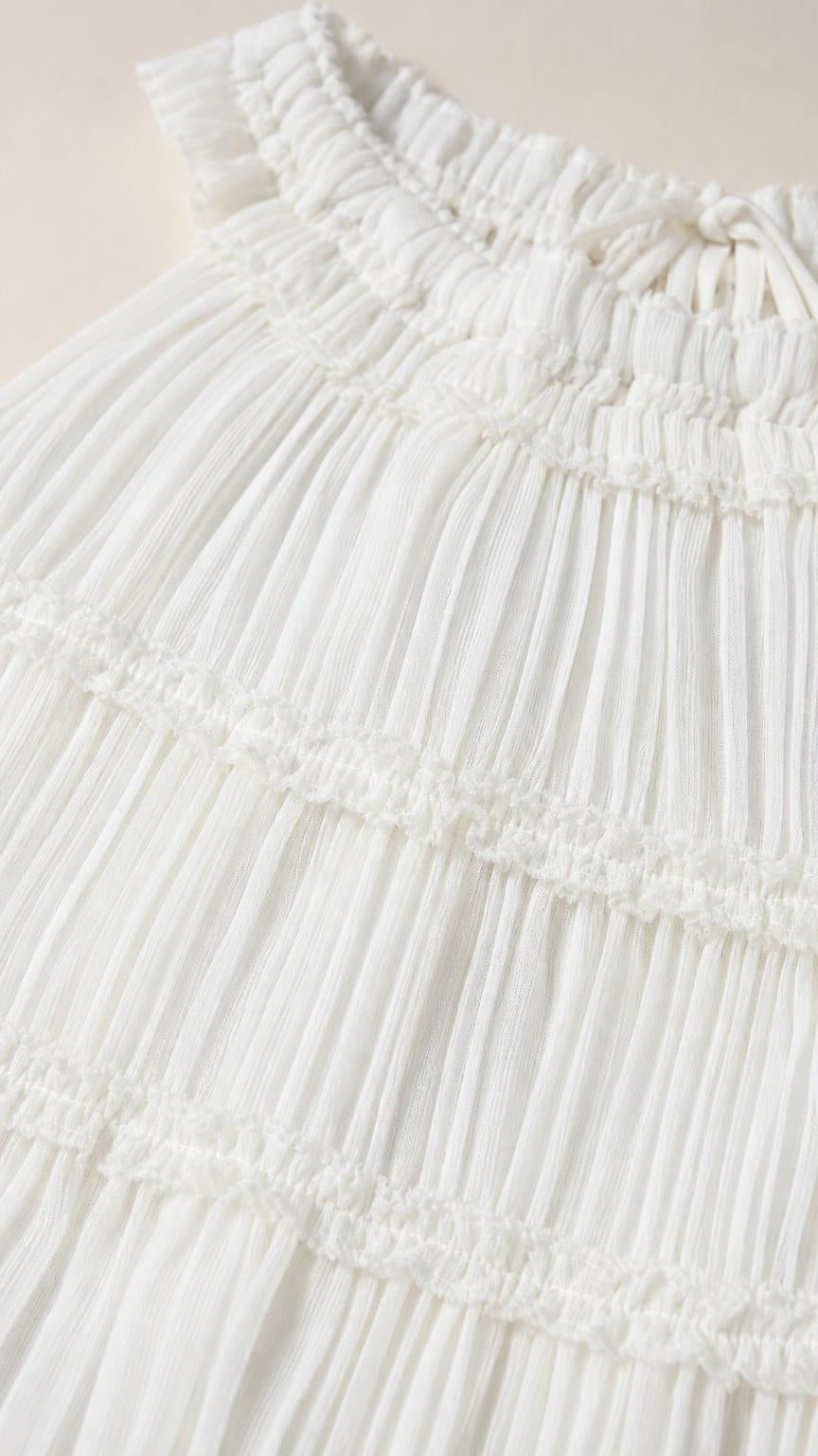 Close-up detail of pleated fabric and neckline on white top