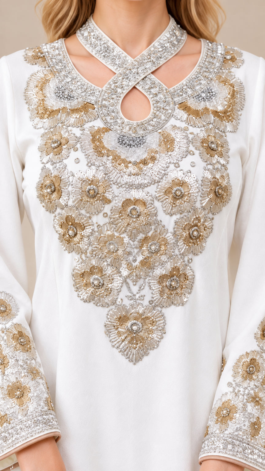 Close-up of intricate metallic beadwork and criss-cross keyhole neckline on white kaftan