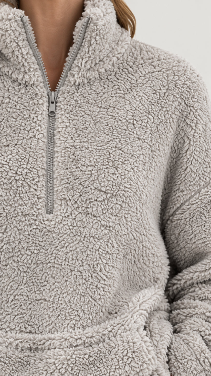 Close-up detail of light gray sherpa fleece fabric, zipper collar, and pocket