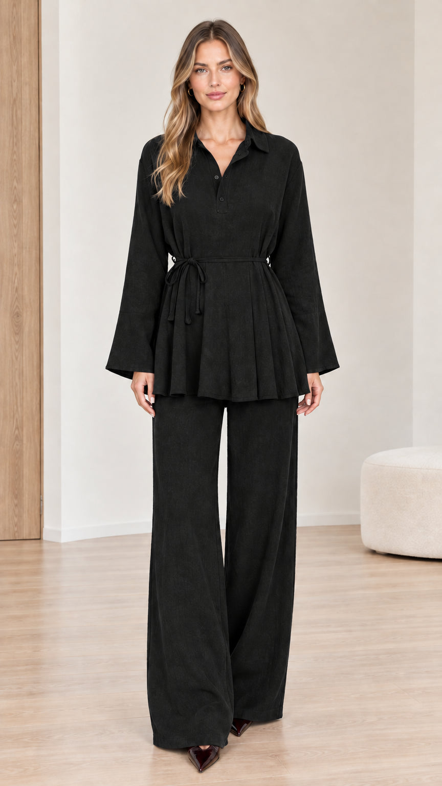 Front view of woman wearing black belted peplum top and wide-leg pants set