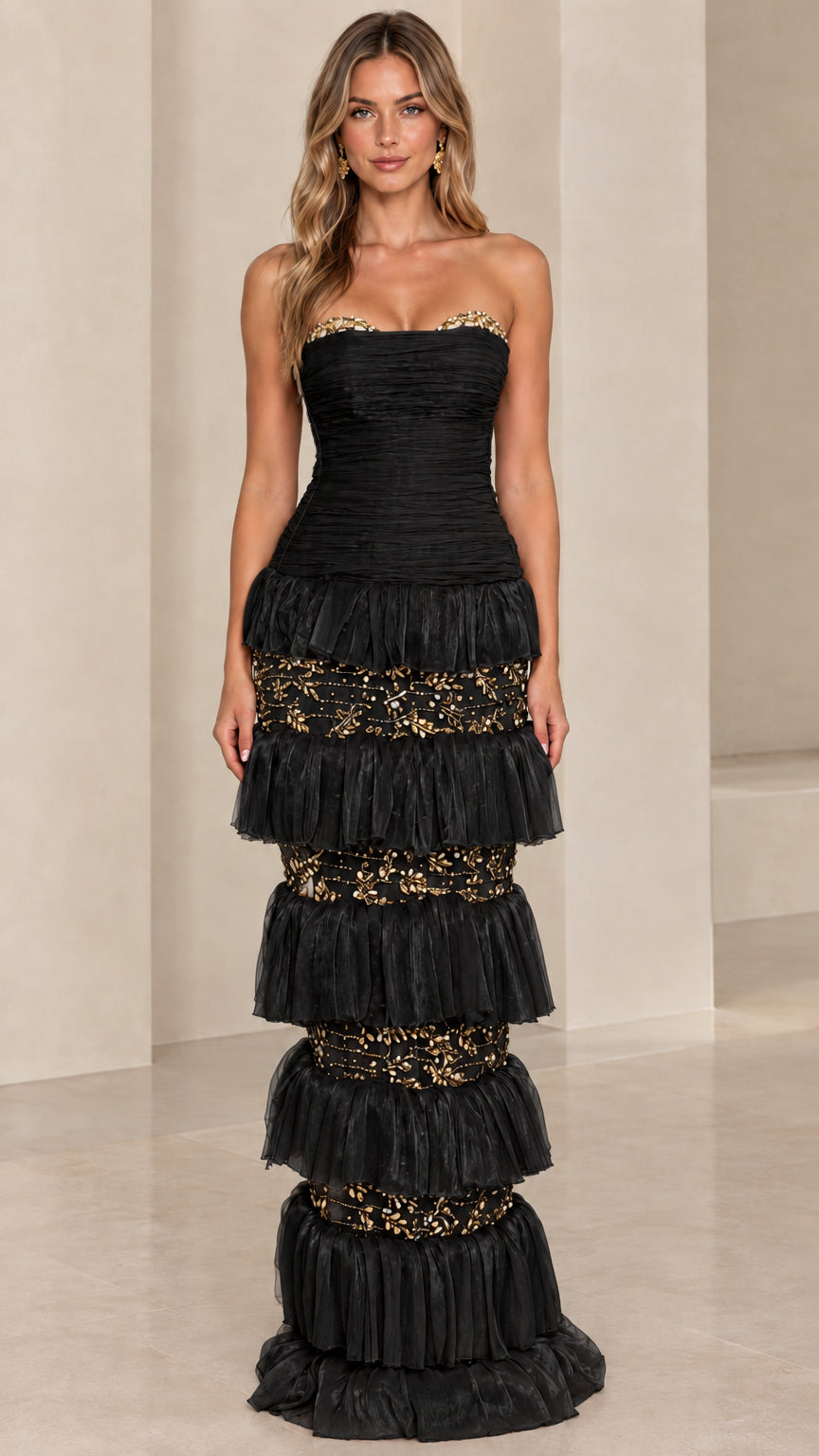 Front view of model wearing Black strapless tiered evening gown with metallic accents