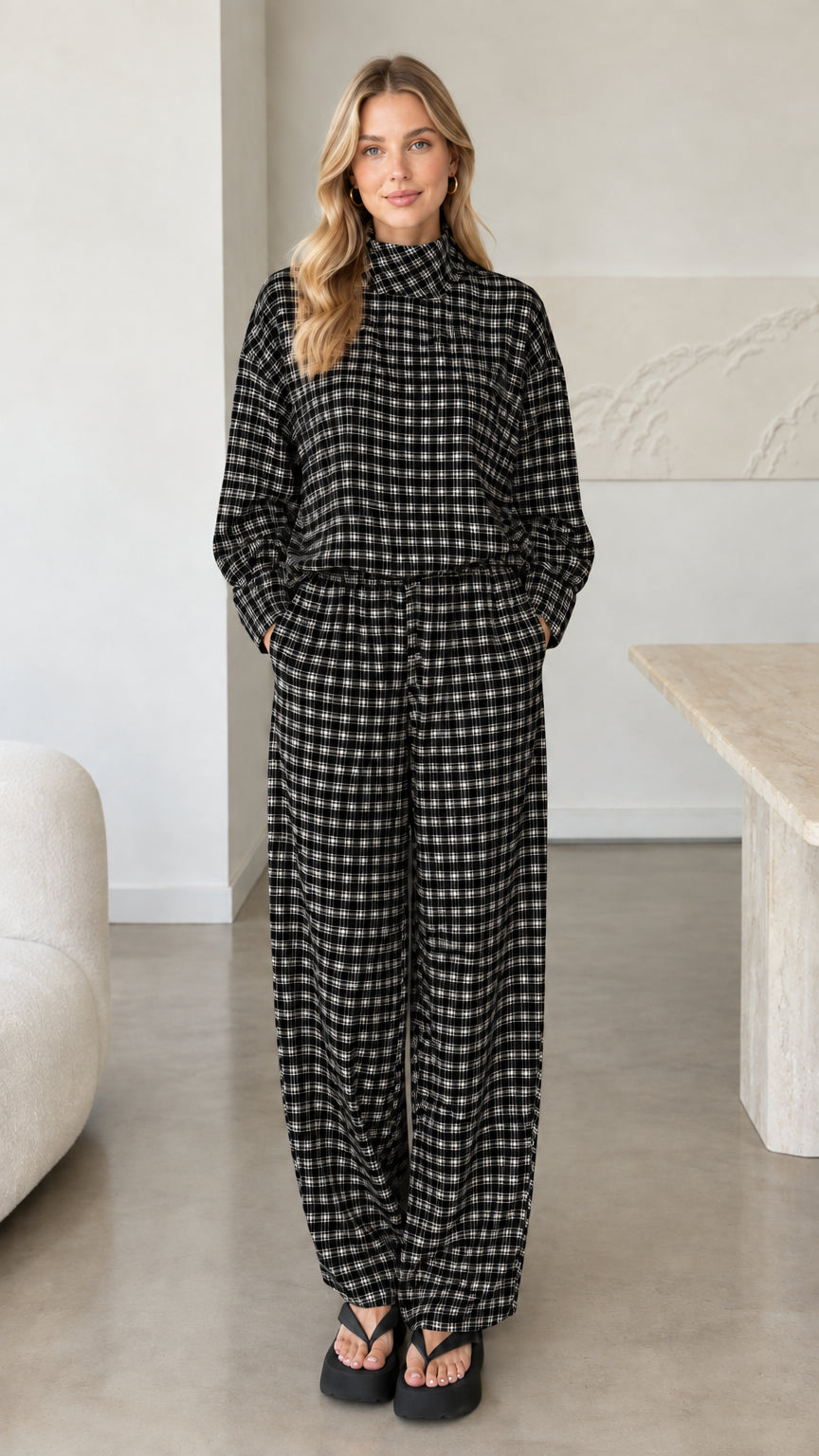 Front view of woman wearing black plaid mock neck top and wide leg pants set