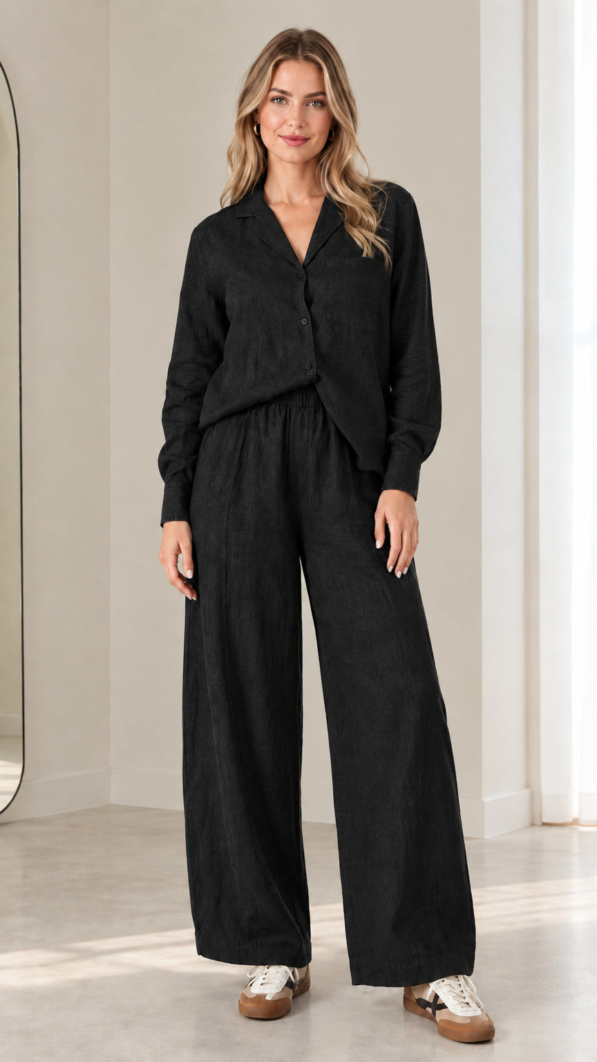 Model wearing black two-piece long-sleeve button-down shirt and wide-leg pants matching set