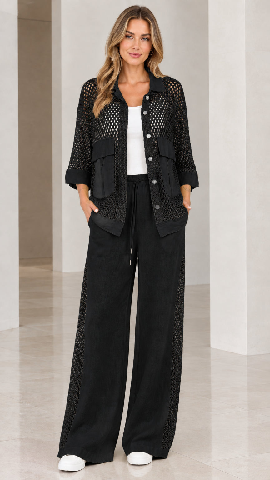 Full front view of woman wearing black open knit shirt and wide-leg trousers set