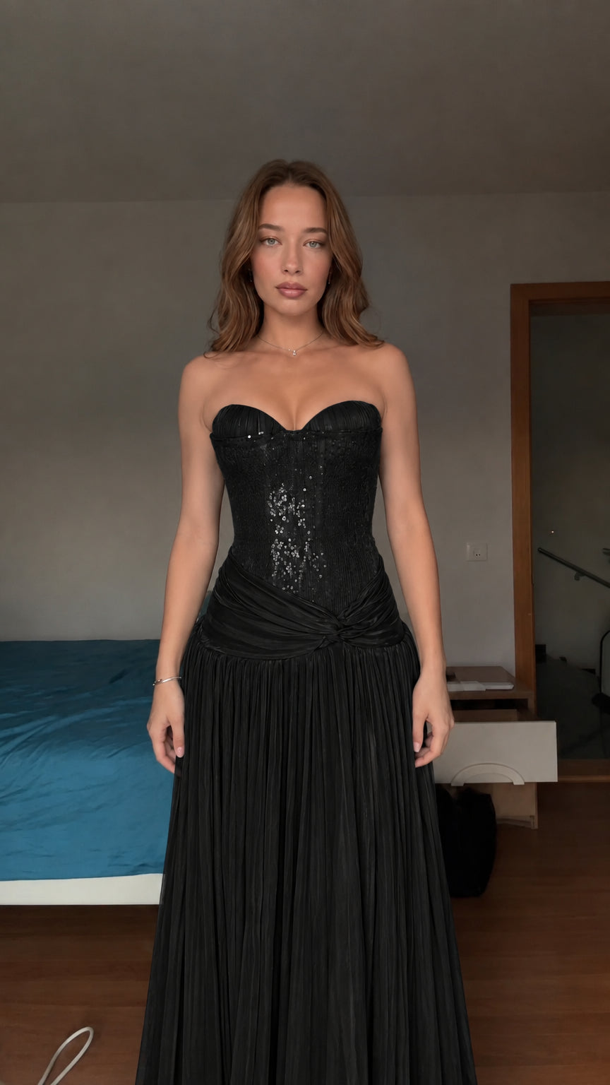 Model wearing black strapless sequin corset pleated evening gown