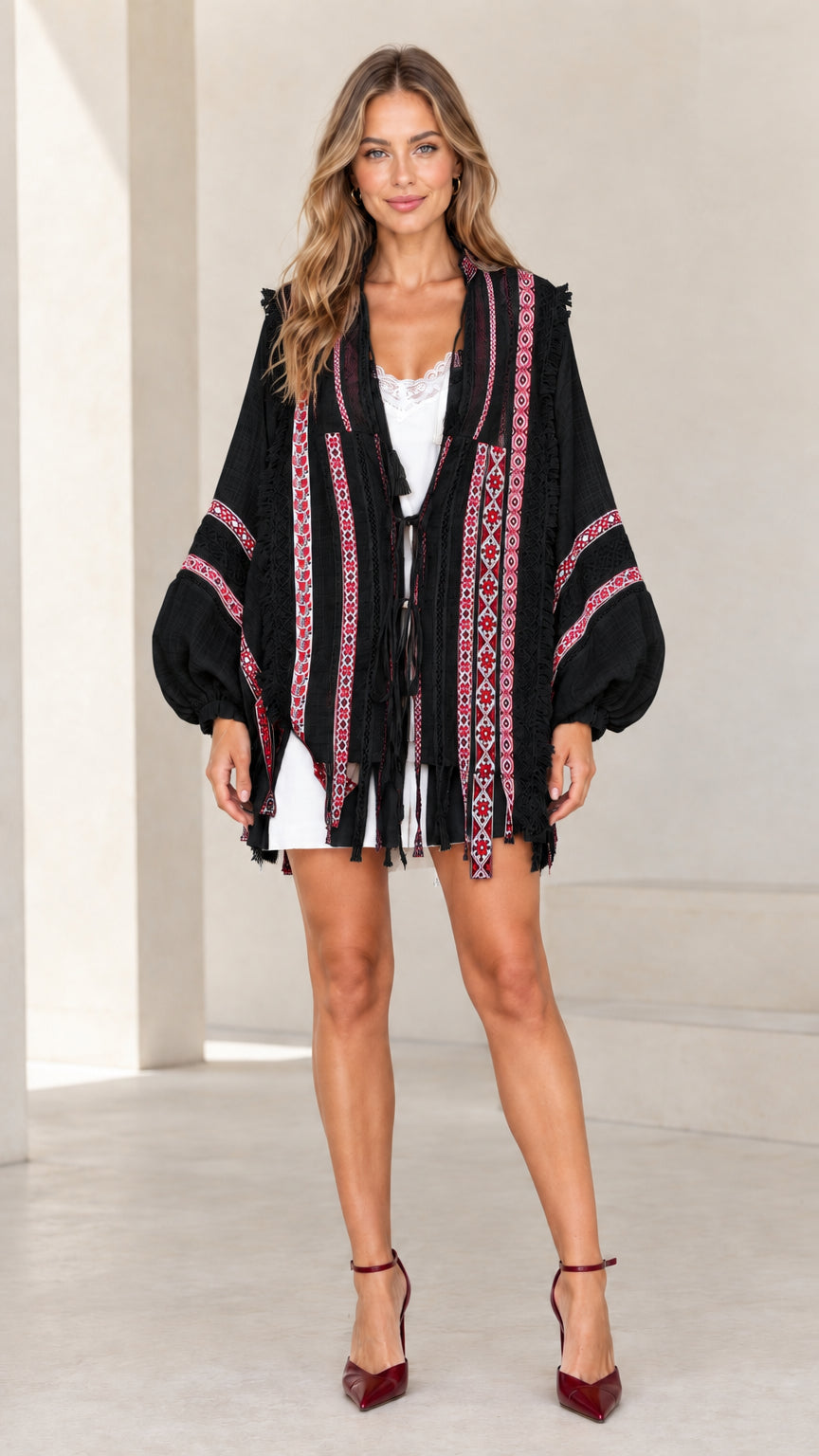 Model wearing black boho embroidered cardigan with contrast red embroidery and fringe trim