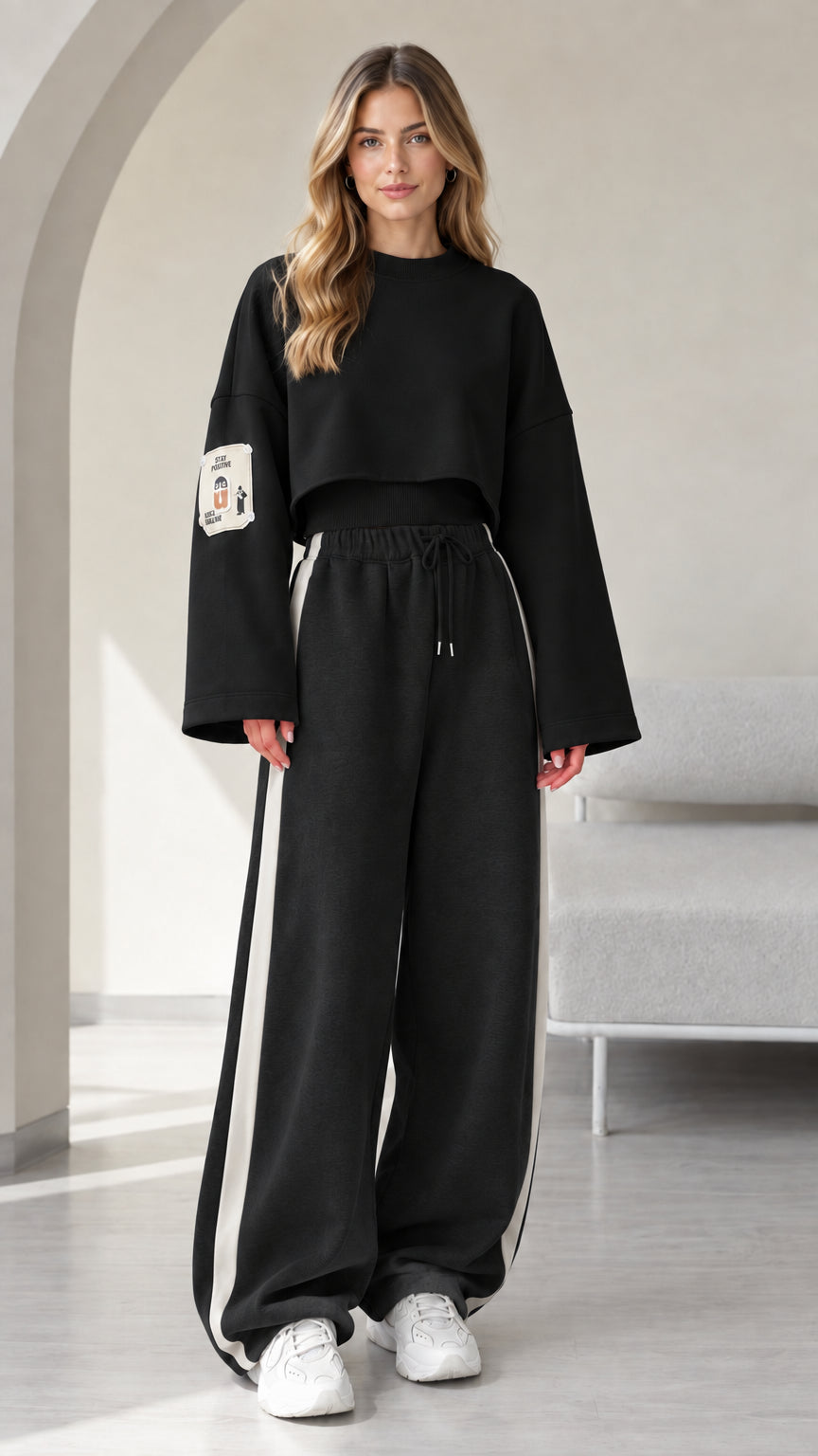 Model wearing black 2-piece cropped sweatshirt and wide leg track pants set with white side stripe