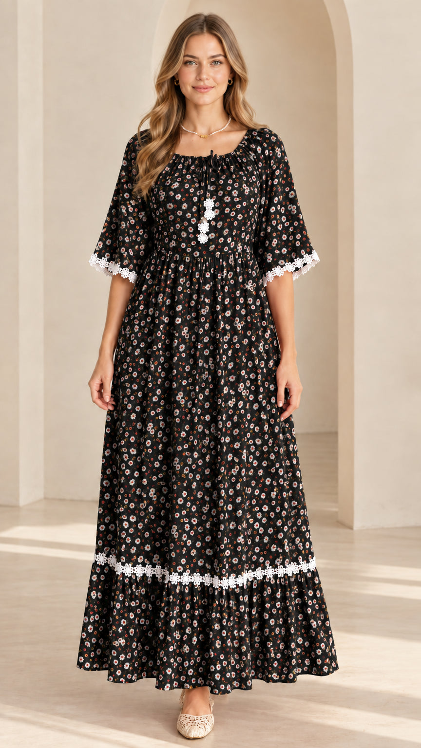 Front view of model wearing black floral tiered maxi dress with white lace trim