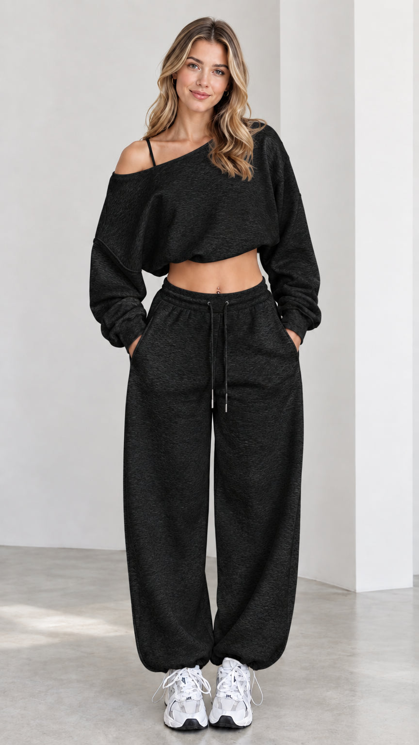 Model wearing black asymmetrical one-shoulder cropped sweatshirt and matching sweatpants set