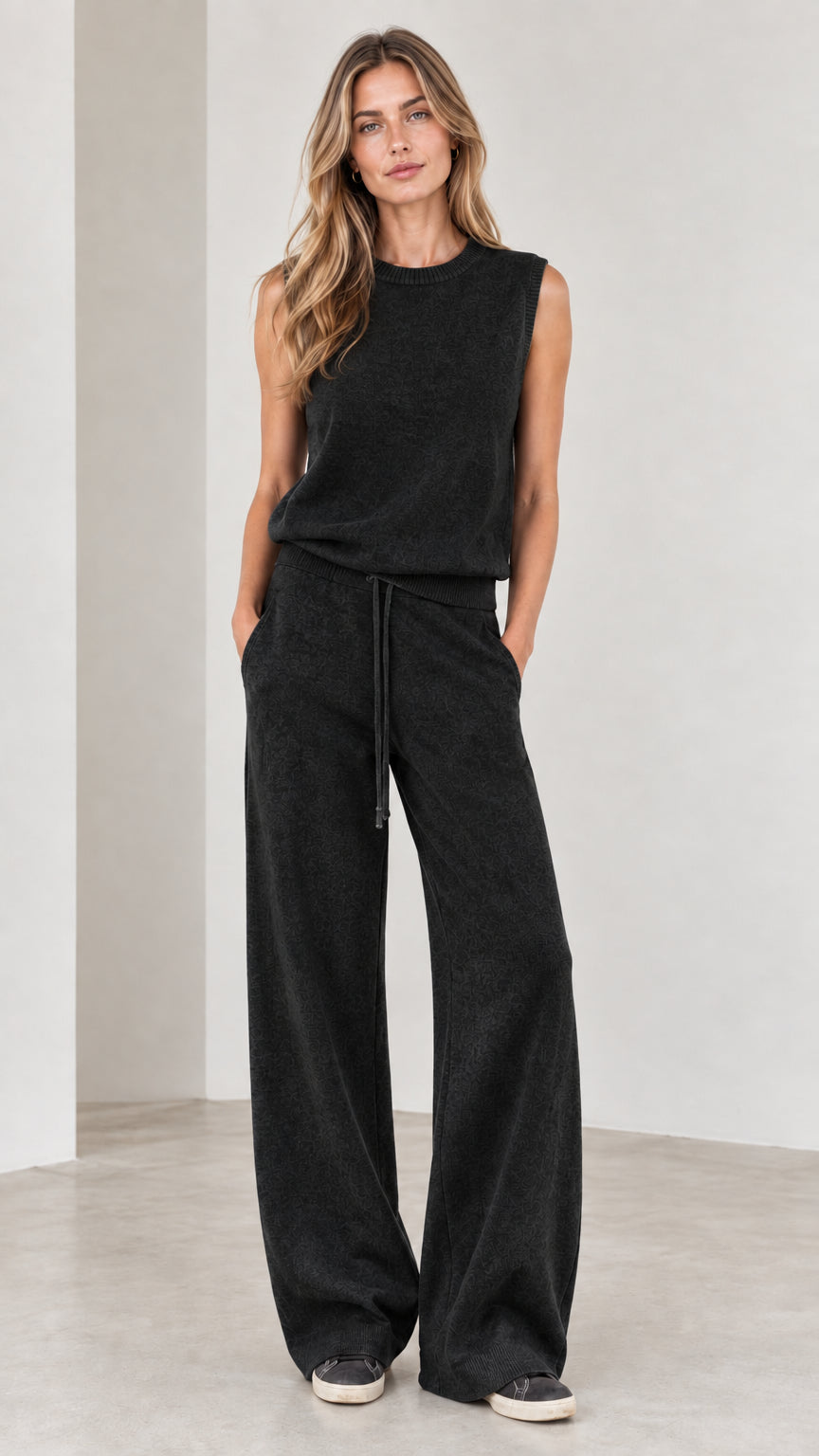 Full-body view of woman wearing Black sleeveless top and wide-leg knit pants set