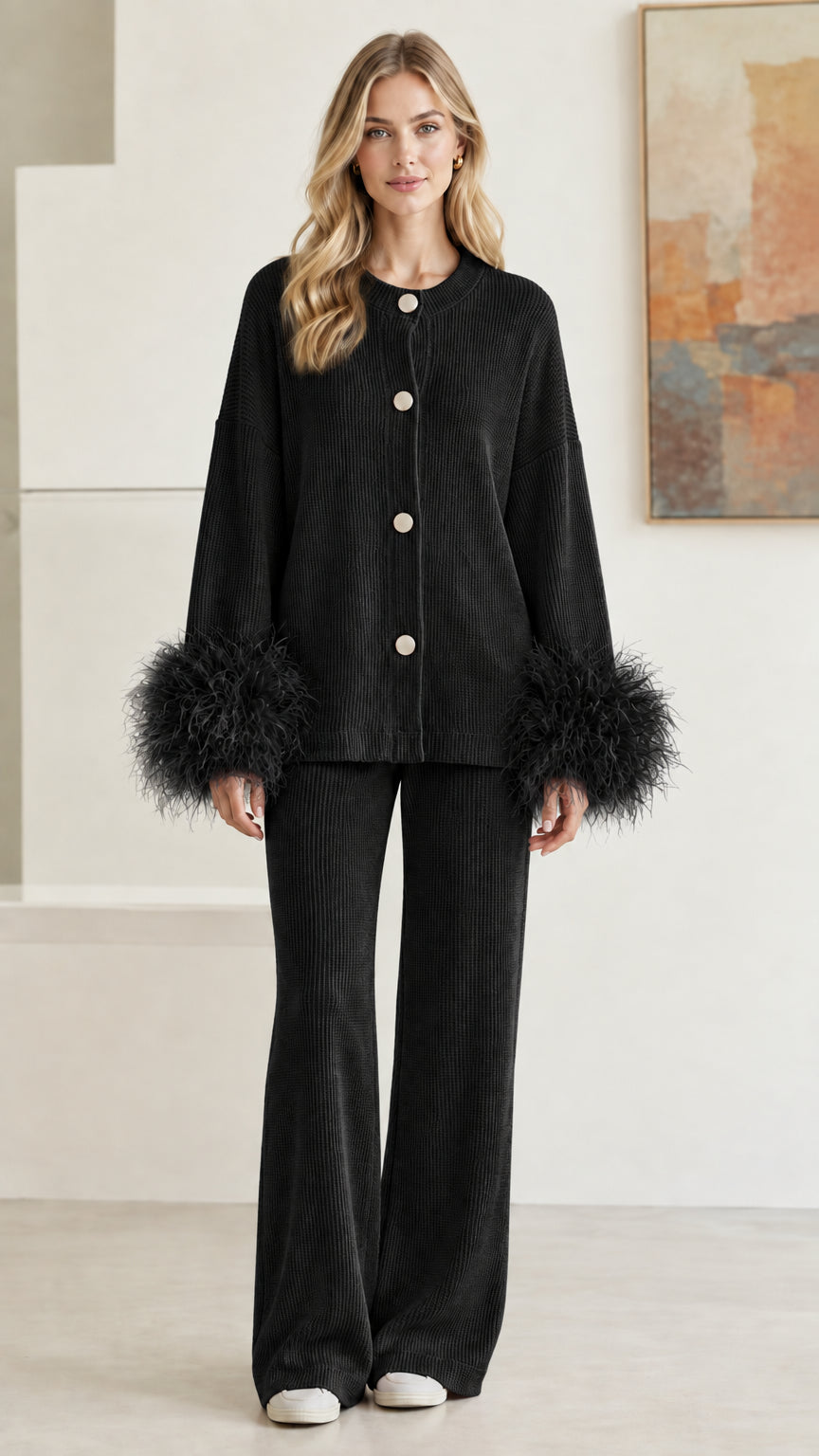 Front view of model wearing classic black ribbed knit two-piece set with feather cuffs