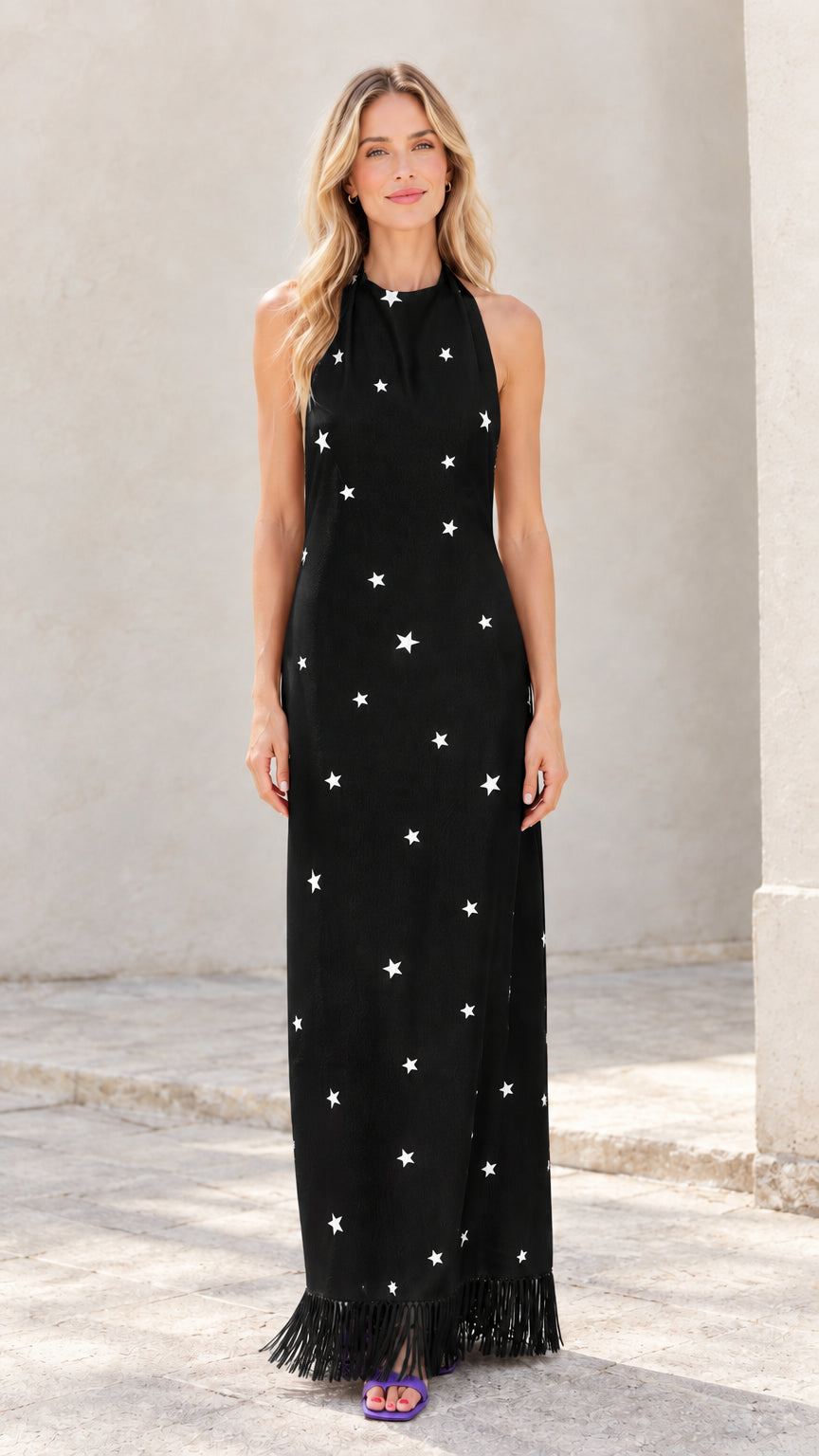Woman wearing black star print halter maxi dress with fringe hem