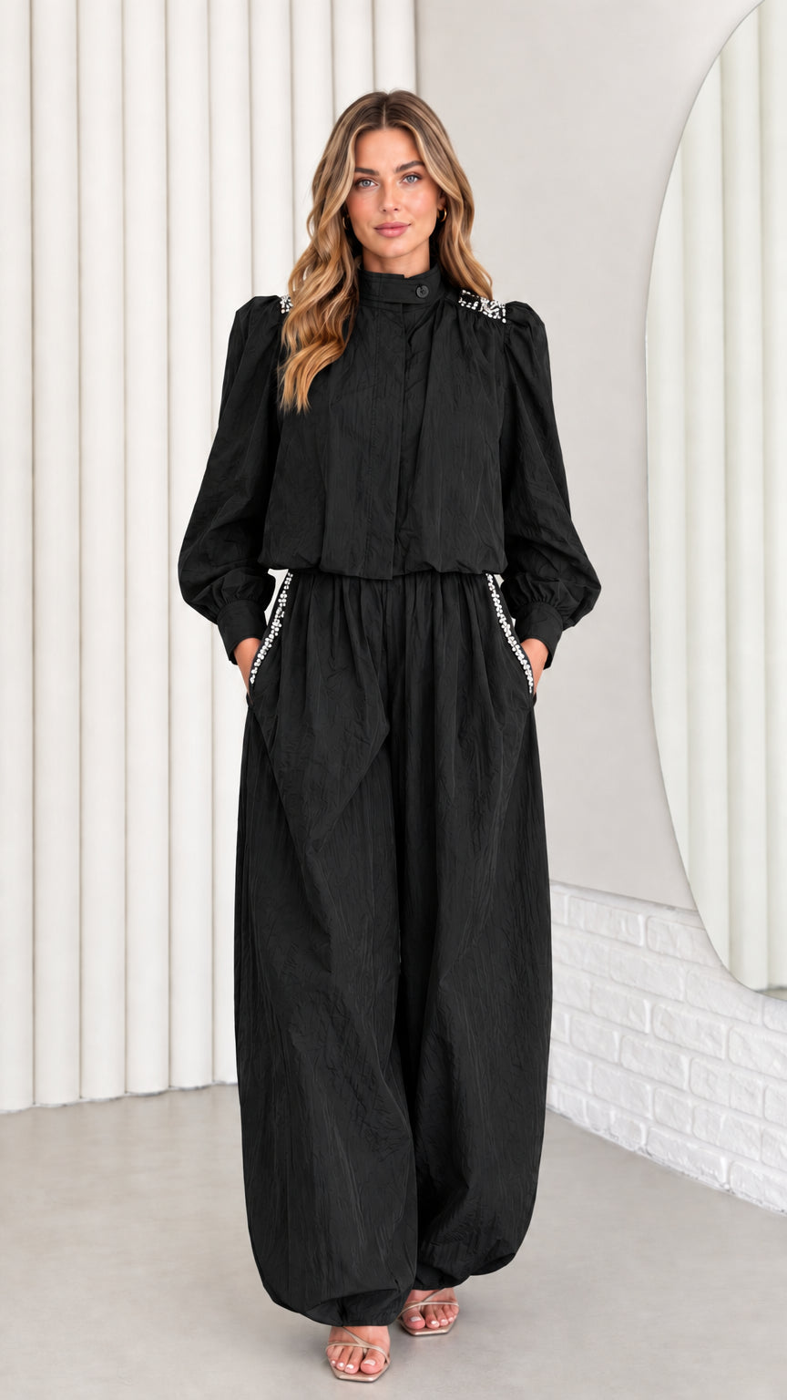 Front view of model wearing black rhinestone mock neck long sleeve jumpsuit