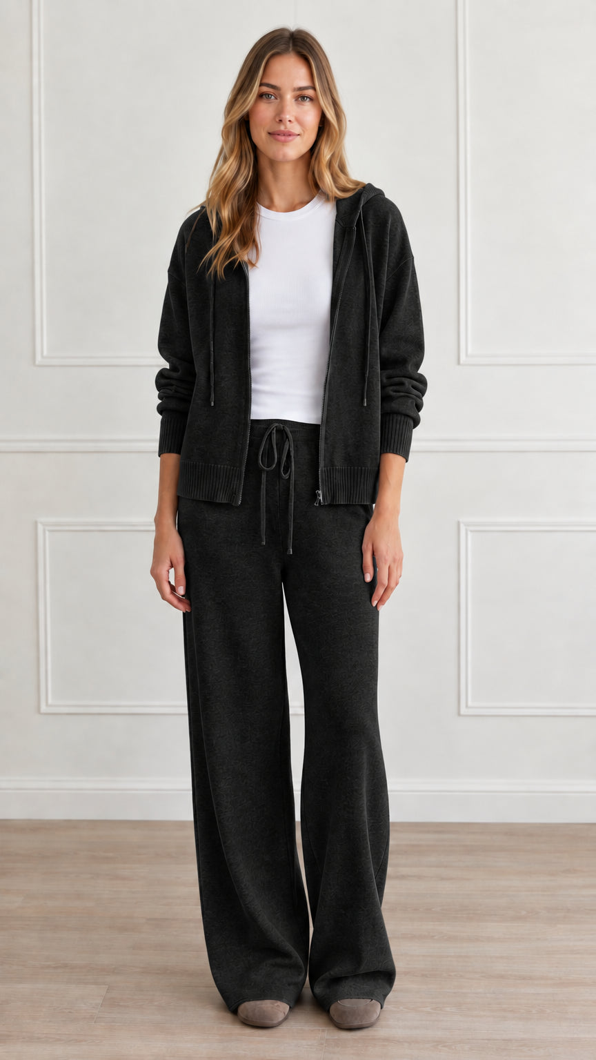Front view of model wearing black knit zip-up hoodie and wide-leg lounge pants set