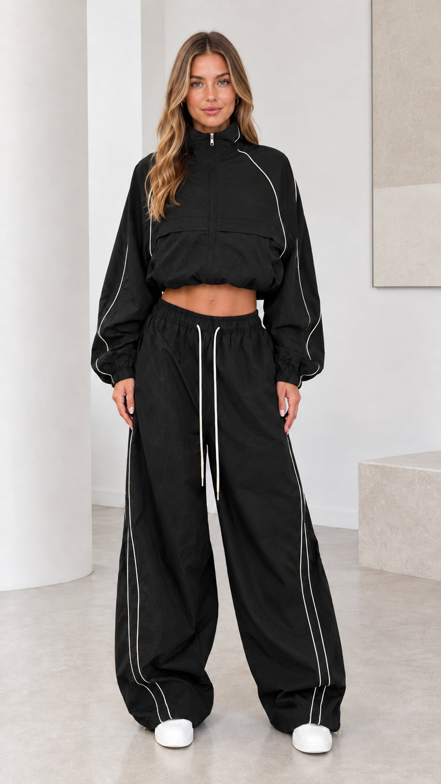 Front view of model wearing black cropped windbreaker and parachute pants set