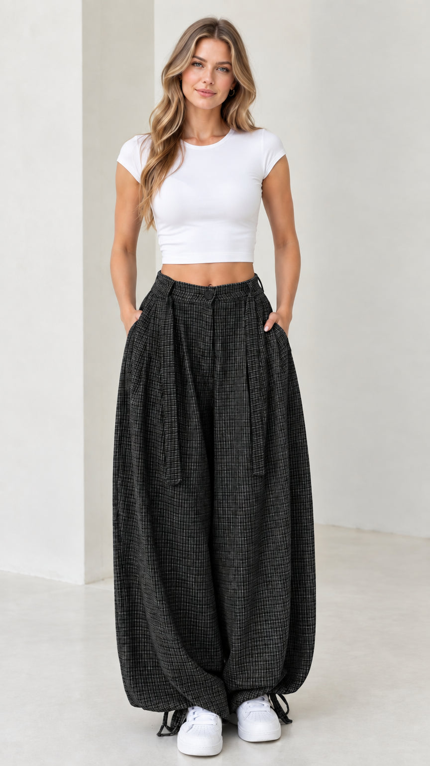 Front view of woman wearing charcoal black micro-plaid pleated balloon pants
