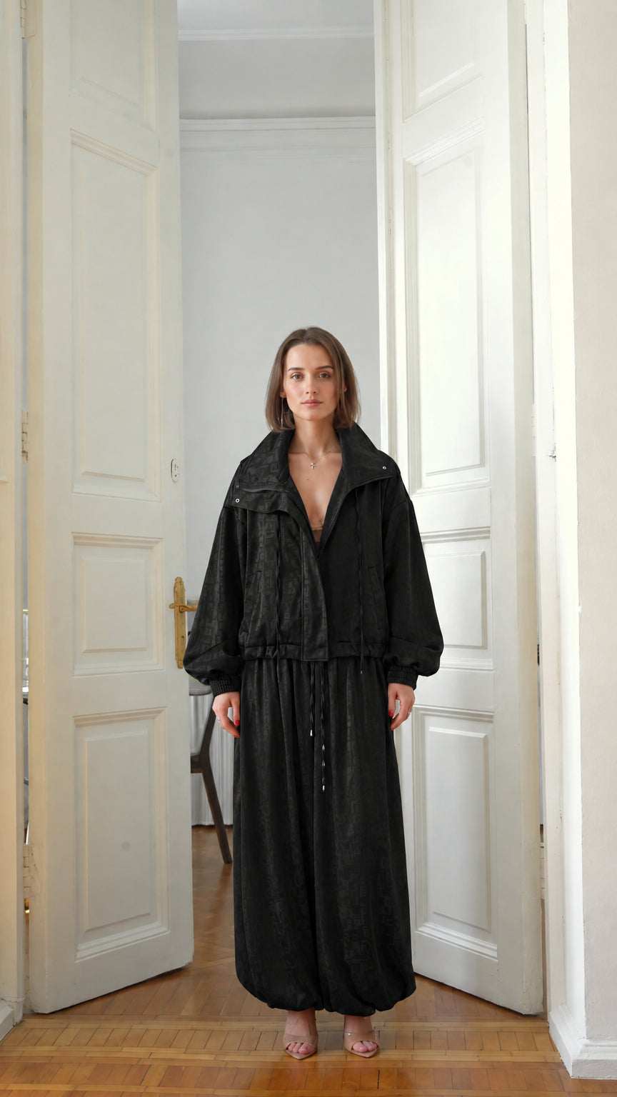 Front view of model wearing classic black zip-up jacket and balloon trousers set