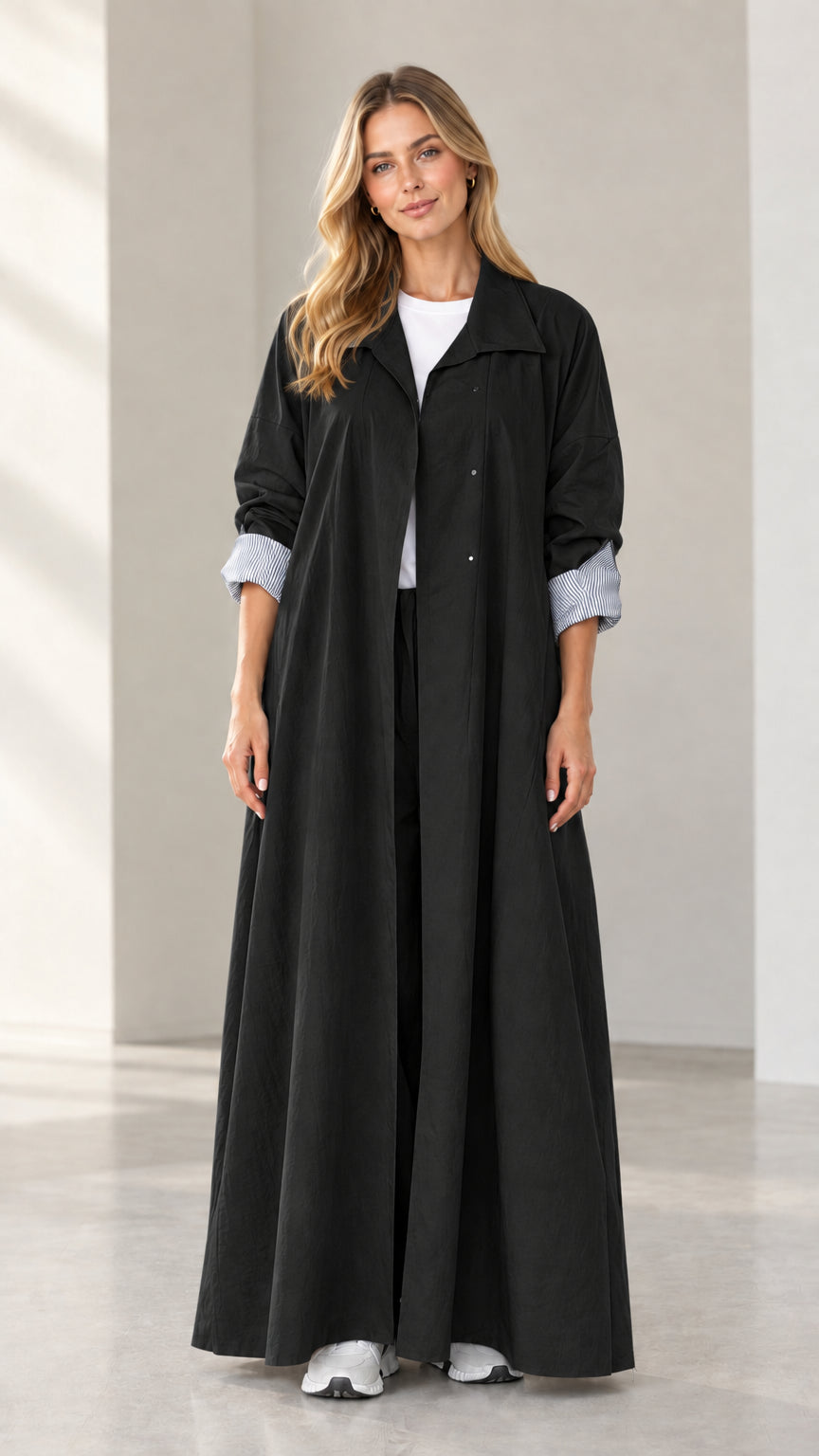 Full-length front view of woman wearing black maxi duster coat with striped cuffs