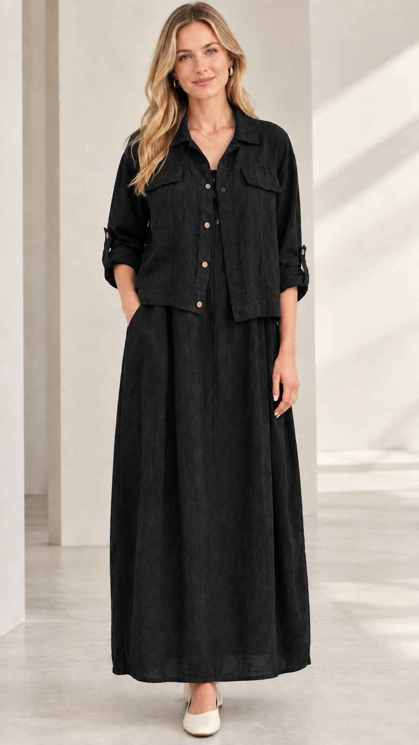 Model wearing black two-piece collared shirt jacket and pleated maxi skirt set