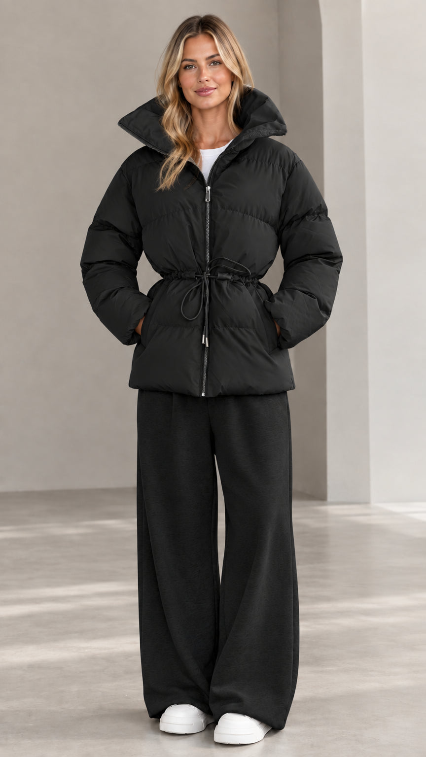 Front view of woman wearing black hooded cinch-waist puffer jacket