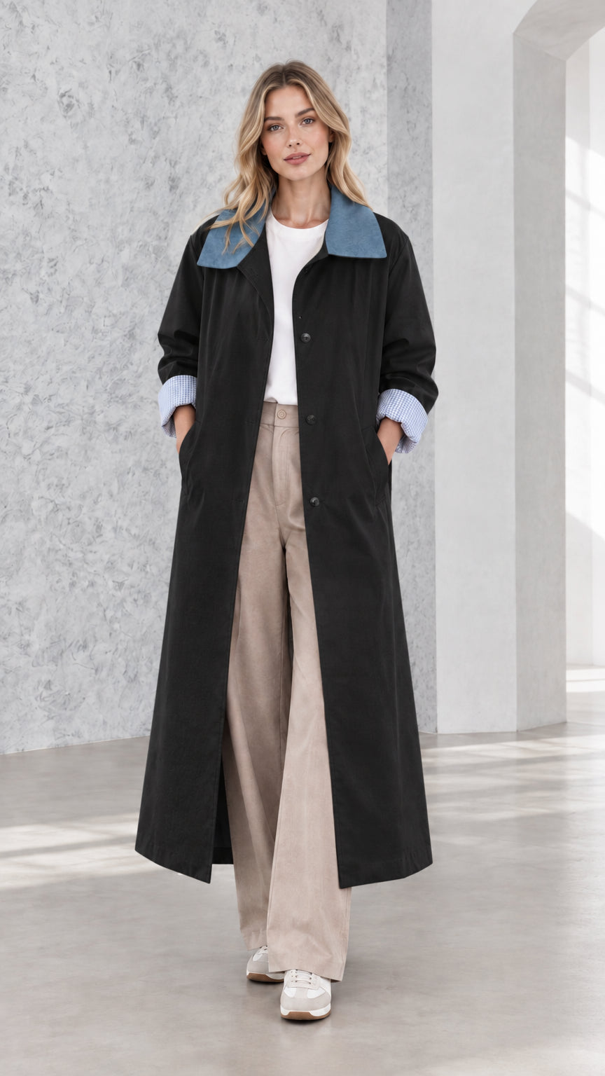Model wearing black maxi trench coat with blue contrast collar and gingham cuffs