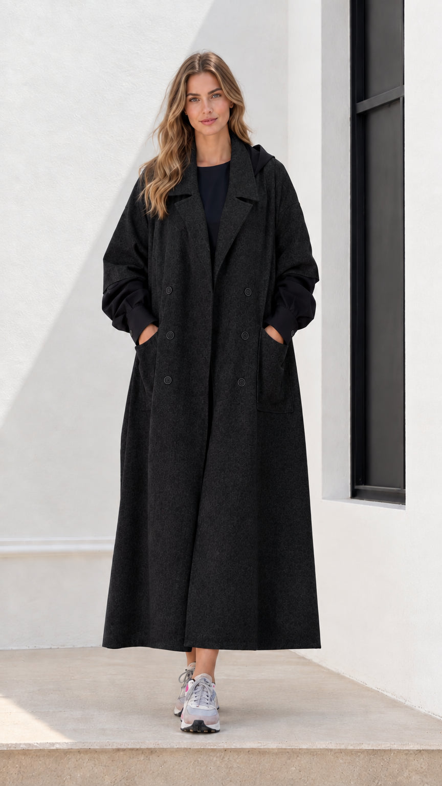 Full-length front view of woman wearing black hooded maxi trench coat