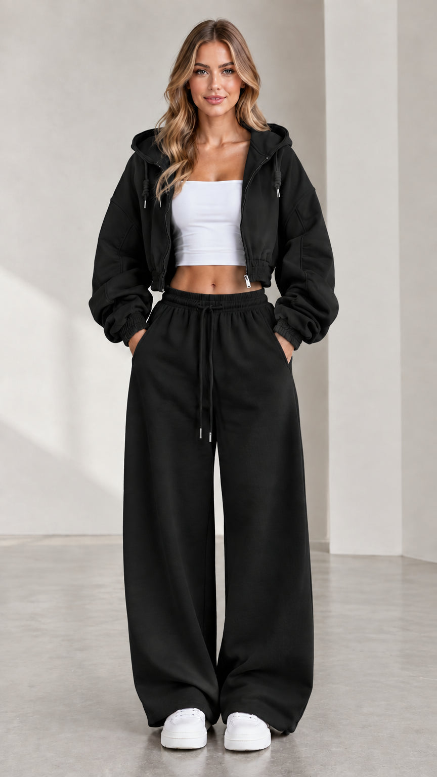 Woman wearing black cropped zip-up hoodie and black wide-leg sweatpants matching set