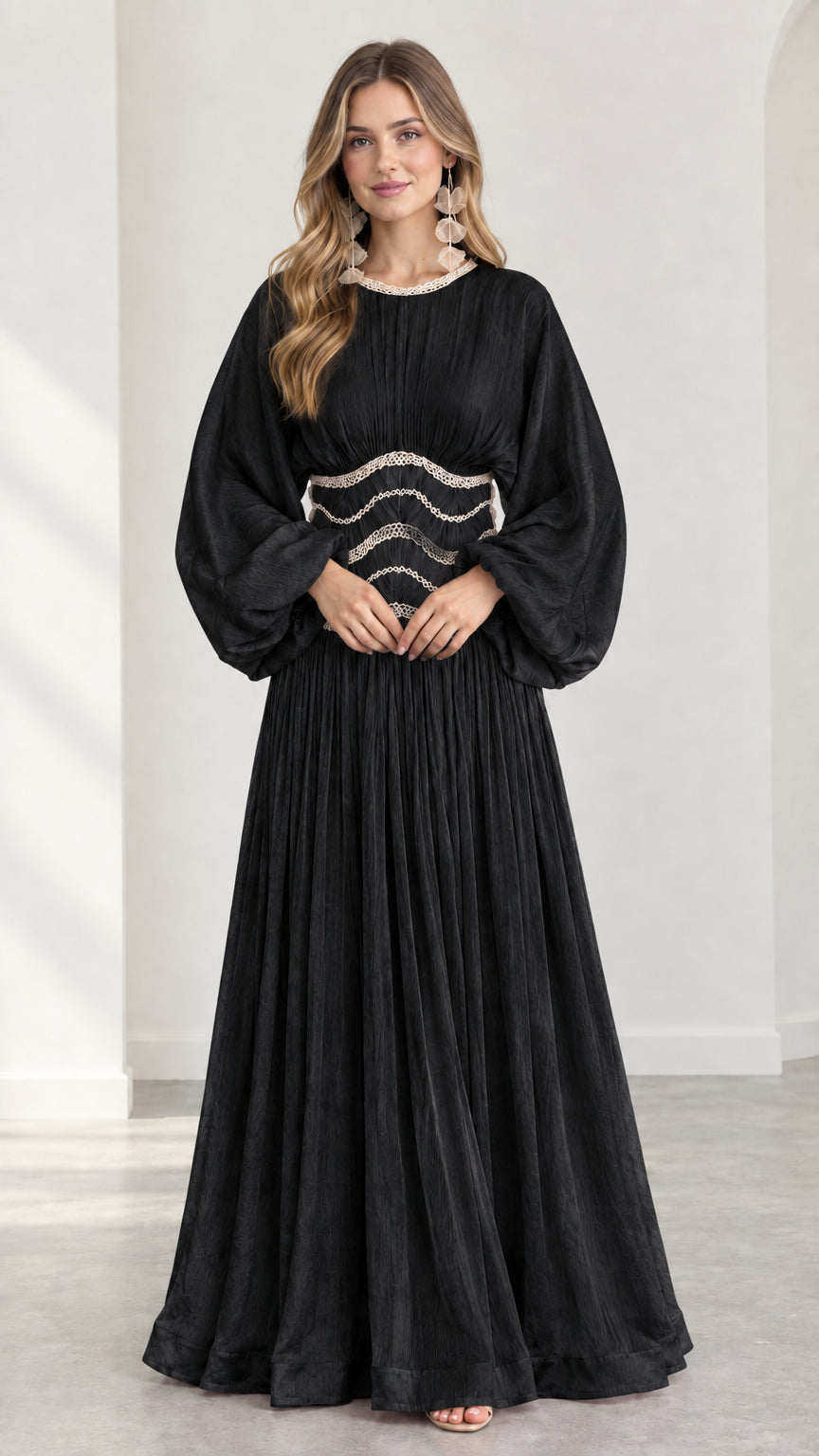 Model wearing black long-sleeve pleated maxi dress with embroidered waist