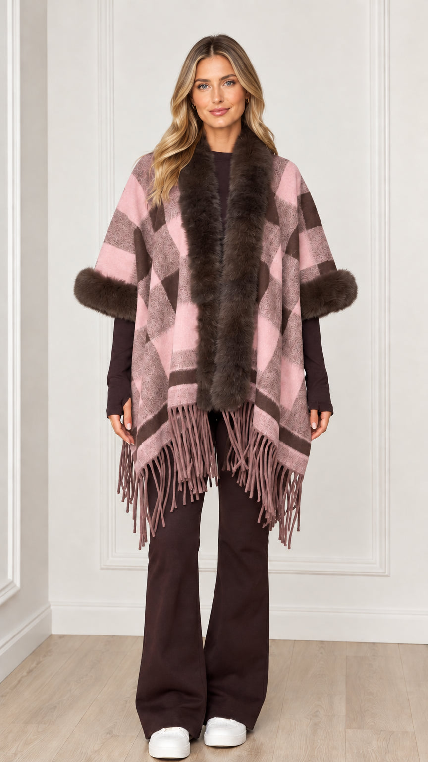 Woman wearing dusty pink plaid poncho wrap with faux fur trim and fringe