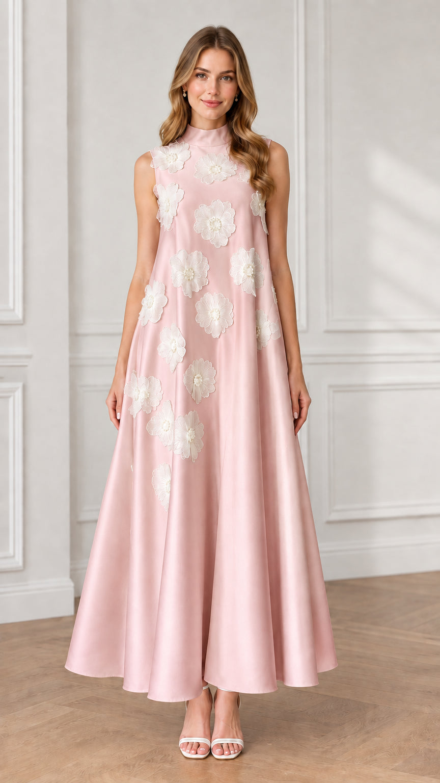 Model wearing blush pink sleeveless high neck maxi dress with white floral appliqués