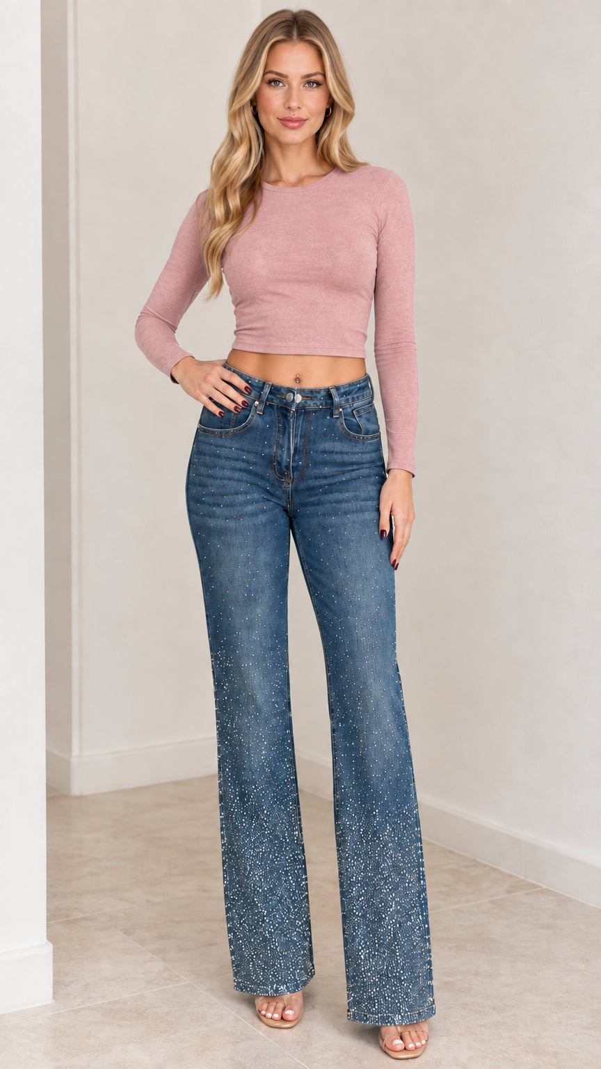 Model wearing medium blue rhinestone flare jeans paired with a pink long-sleeve crop top