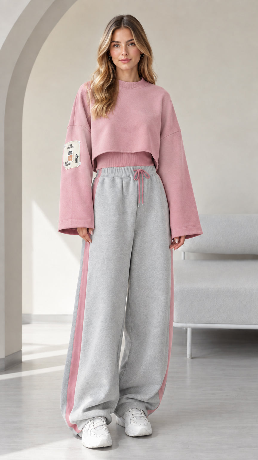Model wearing pink cropped sweatshirt and grey wide leg sweatpants with pink side stripe