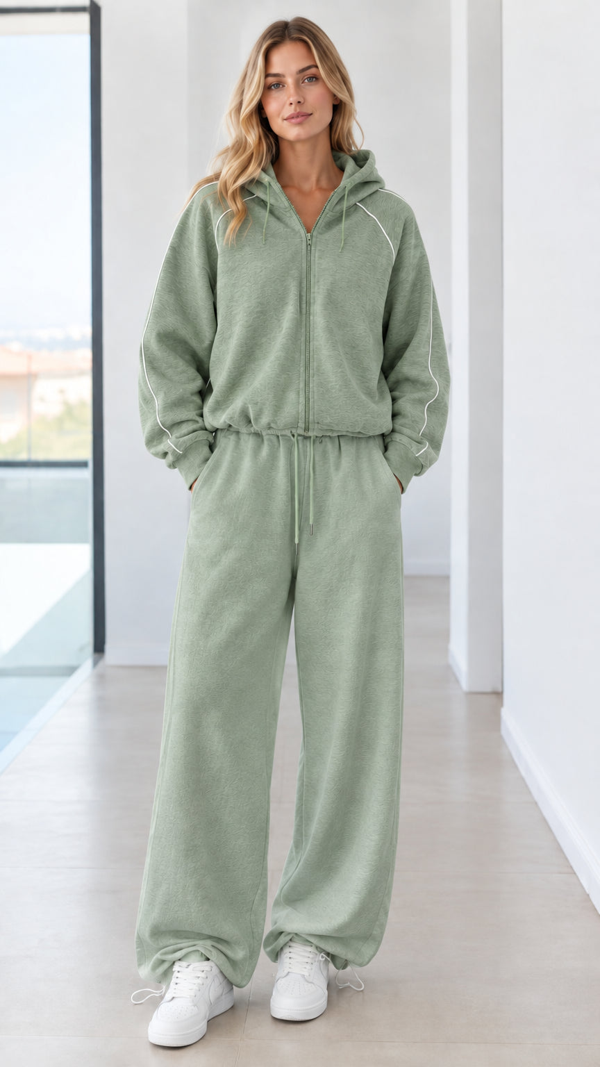 Full body studio shot of model wearing sage green zip-up hoodie and wide-leg sweatpants set