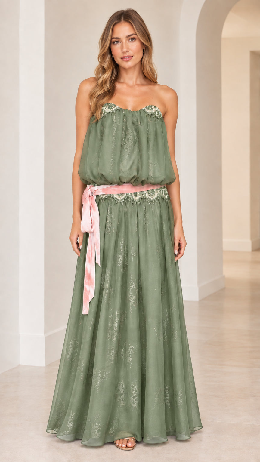 Front view of woman wearing strapless sage green blouson maxi dress with pink sash
