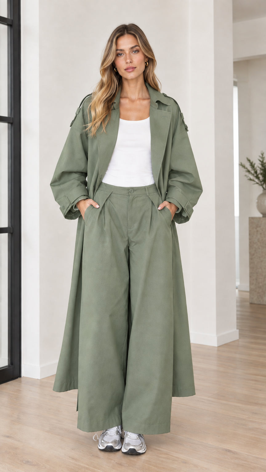 Woman wearing sage green oversized maxi trench coat and matching pleated pants set