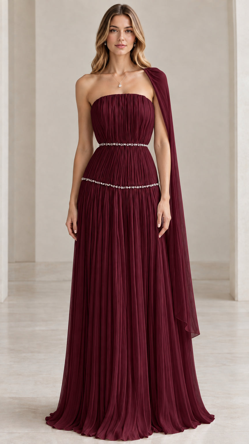 Model wearing burgundy red strapless pleated evening gown with crystal waistband