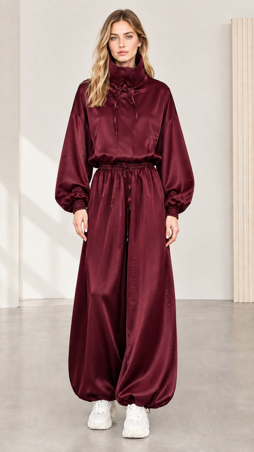 Full front view of model wearing burgundy satin high neck balloon jumpsuit